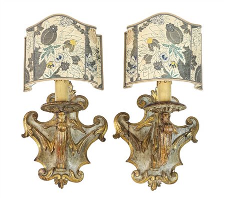 Coppia di applique a una luce in legno intagliato a volute e motivi fogliacei,