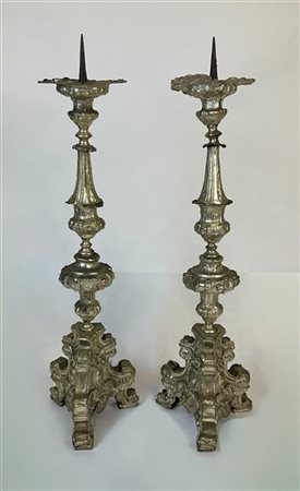 Coppia di candelieri in legno rivestito in metallo argentato decorato a volute
