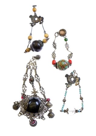  Lotto di quattro amuleti in argento, legno e paste vitree