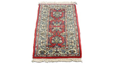 PICCOLO TAPPETO CAUCASICO fondo rosso, campo con motivi vegetali nei toni del...