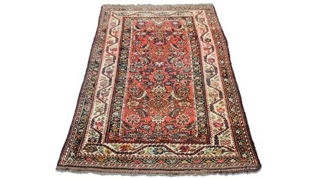 TAPPETO CAUCASICO fondo rosso mattone, campo con motivi floreali nei toni...