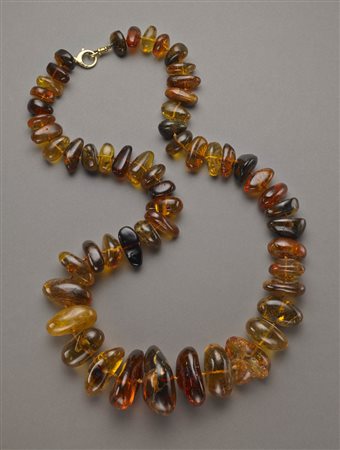 Collana in ambra a guisa di sassi irregolari scalata di tonalità varia, dal...