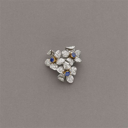 Spilla a tre fiori in oro bianco centrati da zaffiri taglio brillante e...