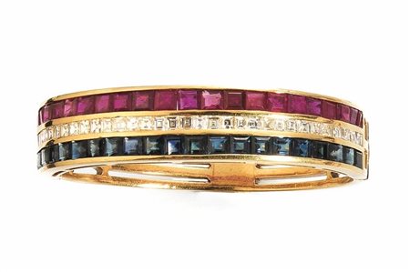 BRACCIALE IN ORO GIALLO, RUBINI, ZAFFIRI E DIAMANTI a cerchio rigido decorato...