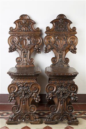 Gruppo di quattro sgabelli in noce con schienali di forma mossa intagliati a...