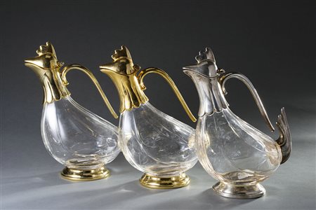 Gruppo di tre versatoi in vetro con ghiere e anse in metallo argentato e...