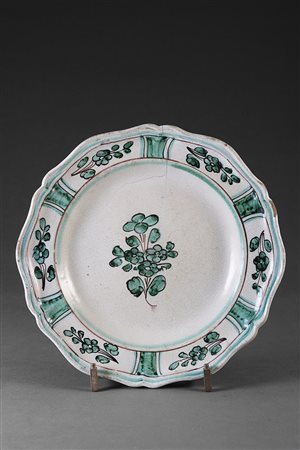 Piatto in maiolica di forma sagomata decorato nei toni del verde. Cavetto...