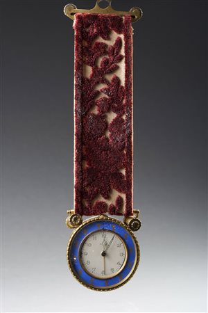 Piccola sveglia da muro con striscia in velluto a fiori. Cassa in metallo...