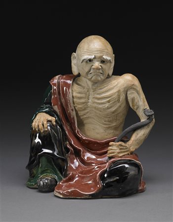 Luohan in ceramica invetriata in marrone, nero e verde, la figura emaciata...