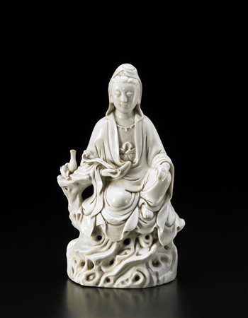 Guanyin in porcellana blanc-de-Chine raffigurata seduta su rocce con un...