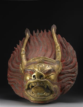 Testa di divinità in bronzo dorato, con lunghe corna, il volto...