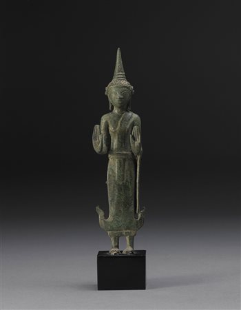 Buddha in bronzo raffigurato in piedi, il volto con espressione sorridente e...