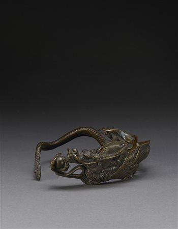 Drago in bronzo in forma circolare, raffigurato mentre afferra la perla sacra...