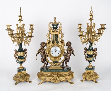 TRITTICO composto da OROLOGIO e da coppia CANDELABRI a sette fiamme in bronzo...