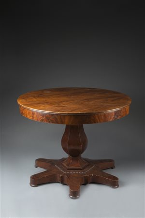 Tavolo lastronato in noce con gamba centrale a colonna sfaccettata poggiante...