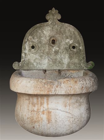 Fontana da muro di forma bombata in marmo bianco sorretta da colonna tornita....