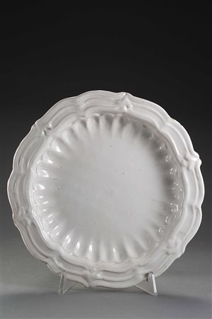 Piatto tondo a bordo mistilineo, leggermente concavo e costolato in maiolica...