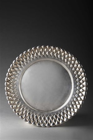 Piatto di forma tonda in argento decorato nel bordo a motivi geometrici....