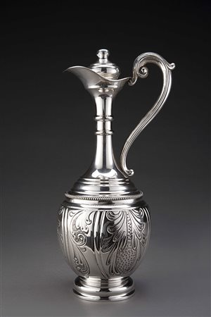 Acquamanile in argento cesellato a motivi vegetali con manico sagomato. Tappo...