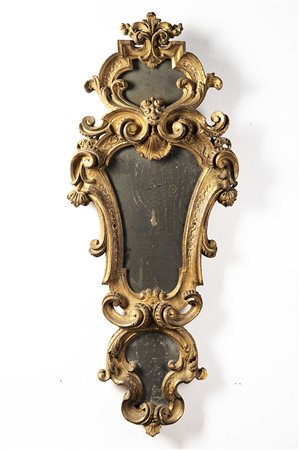 Specchio di forma sagomata in legno intagliato e dorato a volute e fiori Sec....