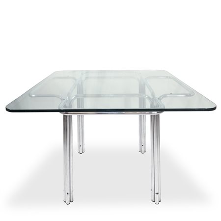 Gruppo DAM  per Busnelli - Tavolo modello Topos con struttura in metallo cromato argentato che partendo da terra si apre come un fiore per sostenere un piano quadrato in cristallo