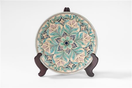 Piatto in maiolica policroma con decoro geometrico floreale nei toni dell'azzurro, del blu e del lilla. Manifattura Giotto, Monte San Savino (Arezzo), secolo XX