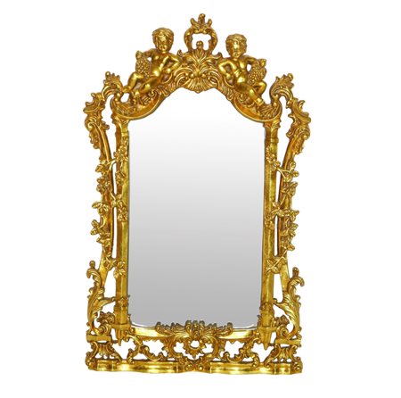Specchiera sagomata entro cornice dorata riccamente decorata a traforo con due bacchini alla sommità