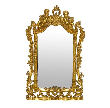 Specchiera sagomata entro cornice dorata riccamente decorata a traforo con due bacchini alla sommità