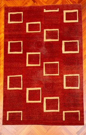 Tappeto a campo color ruggine, decorato da motivi geometrici quadrangolari color avorio disposti in sequenza regolare. Fine secolo XX/inizio XXI