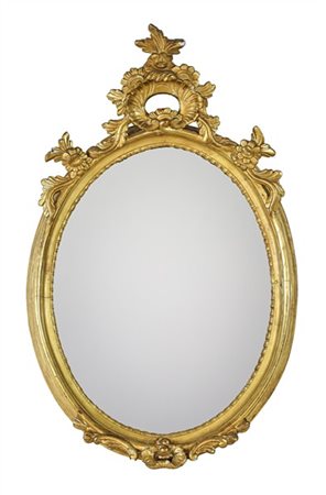 Specchiera di forma ovale in legno intagliato e dorato con cimasa e grembiale d