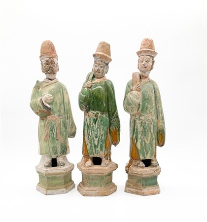 Tre figure di attendenti in terracotta con invetriatura Sancai, su sostegno esa