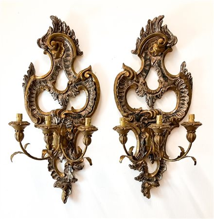 Coppia di applique a tre luci in legno intagliato a foglie e volute, laccato e