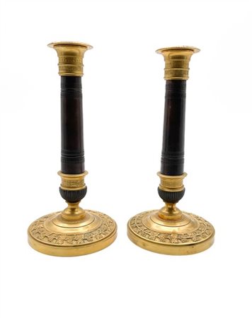 Coppia di candelieri in bronzo dorato e brunito decorati a foglie di vite e mot