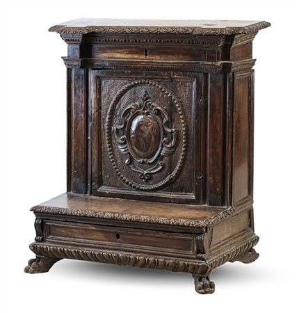 Inginocchiatoio in noce con fronte ad un'anta intagliata a scudo entro riserva