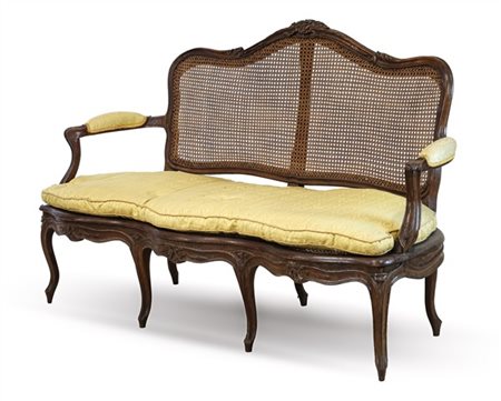 Divano in noce intagliato con schienale sagomato e braccioli mossi terminanti a