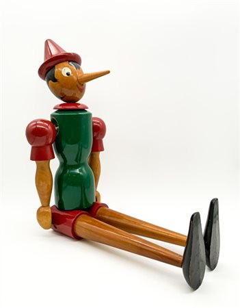 Figura di Pinocchio seduto in legno dipinto in policromia con braccia e testa m