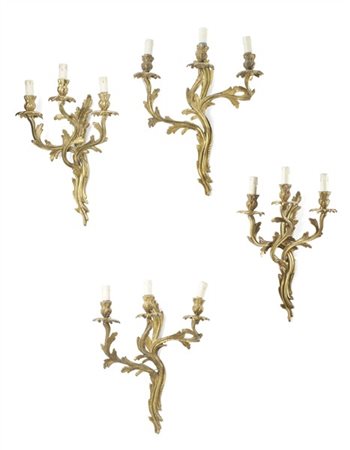 Gruppo di quattro applique a tre luci in bronzo dorato con bracci mossi decorat