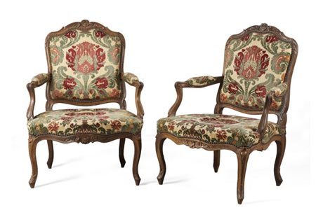 Coppia di poltrone in noce intagliato con fascia e schienale sormontato da fogl