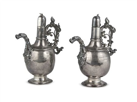 Coppia di ampolle liturgiche in argento con tappo a vite, anse decorate a volut