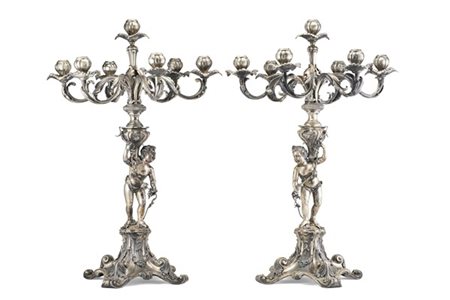 Coppia di candelabri in argento sbalzato a sette luci con fusto in forma di Bac
