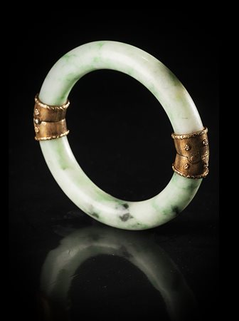 Un bracciale in giadeite verde mela con marezzature più scure, con montatura...