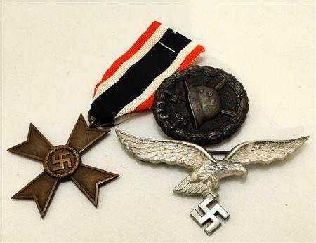  
Lotto composto da KVK per meriti civili, un distintivo di ferita 1GM e di un aquila per tenuta estiva della Luftwaffe prima metà XX sec.
 