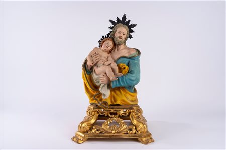 San Giuseppe con Bambino, scultura in terracotta policroma con applicazioni in metallo argentato. Su base in legno dorato traforata a volute e corolle di fiori. Napoli, secolo XIX.