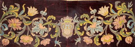 Pannello su velluto con decoro policromo in seta e fili d’argento a girali di foglie e fiori e stemma. Entro cornice in legno intagliato e dorato. Secolo XIX.