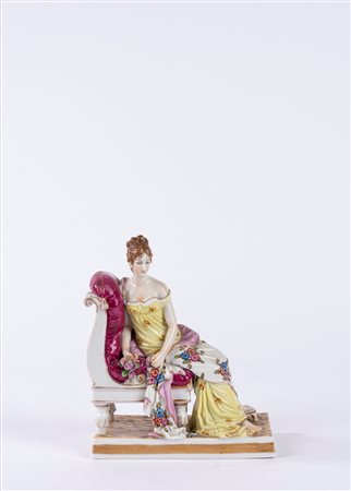 Gruppo in porcellana policroma raffigurante Madame Juliette Récamier adagiata su una chaise longue, su una base rettangolare decorata a finto marmo. Manifattura tedesca, fine secolo XIX/XX.