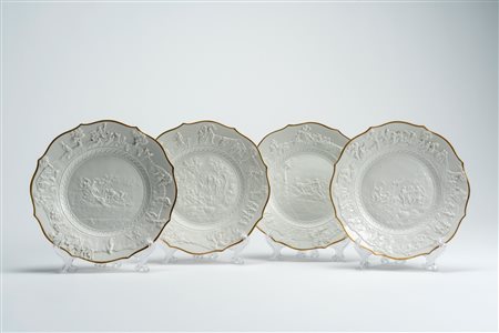 Quattro piatti in porcellana bianca a basso rilievo con profilo mistilineo dorato. Manifattura di Capodimonte, fine XIX secolo