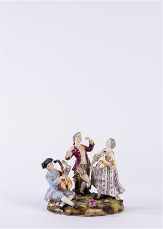 Gruppo in porcellana policroma raffigurante scena galante con suonatore di chitarra su zolla erbosa con fiori. Manifattura tedesca, fine secolo XIX/XX.