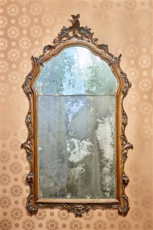 Specchiera di forma mossa in noce intagliato con fregi traforati a volute fogliate. Veneto, secolo XVIII