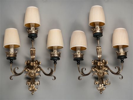 Coppia di appliques in metallo argentato a tre luci con bracci mossi a volute di foglie e fiori