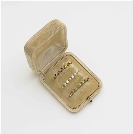 Lotto composto da tre spille da balia in oro giallo, una con smeraldi, una...